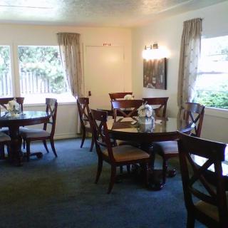 A cozy dining room with elegantly arranged tables and chairs, surrounded by windows with curtains.