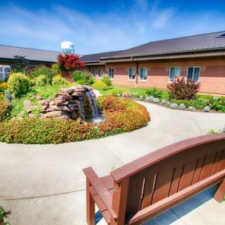 A peaceful garden with a waterfall, surrounded by a pathway and seating area.