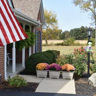 A charming house entrance with an American flag and colorful flowers in planters.