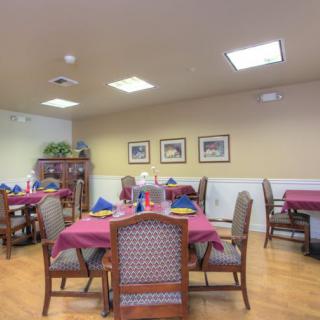 A well-arranged dining room with tables set for a meal, featuring elegant decor and framed artwork on the walls.