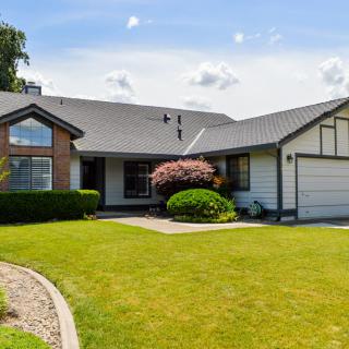 A charming single-story house with a well-maintained lawn and front yard on a sunny day.