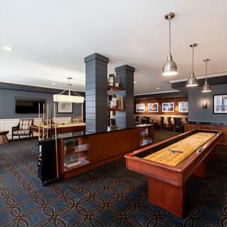 A modern game room with a shuffleboard table and comfortable seating.