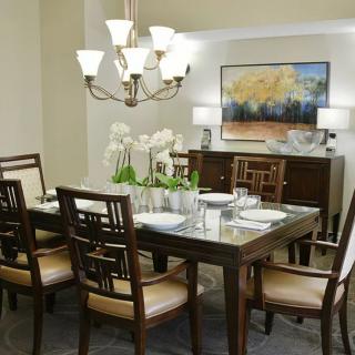 A well-decorated dining room with a wooden table, cushioned chairs, and an elegant chandelier.