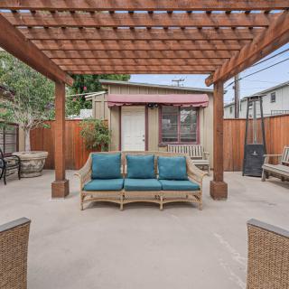 A cozy outdoor patio with a wooden pergola and cushioned seating.
