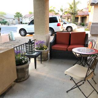 A cozy patio setup featuring a comfortable sofa, small table, and decorative plants.