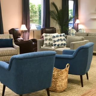 A cozy living room area featuring various chairs, sofas, lamps, and decor.