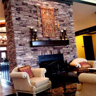 A cozy living room with a stone fireplace and elegant armchairs.