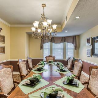 A well-decorated dining room with a large table set for guests beneath an elegant chandelier.