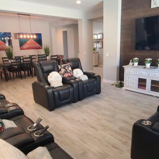 A modern living room with leather recliners, a large TV, and an adjacent dining area.