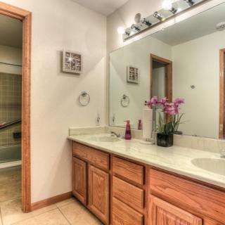 A clean and well-organized bathroom with a double sink vanity and wooden cabinets.