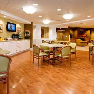 A cozy indoor lounge area with tables, chairs, a coffee station, and a television.