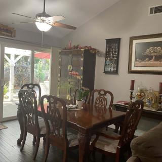 A cozy dining area featuring a wooden table with chairs, surrounded by elegant decor and a glass cabinet.
