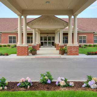 A building entrance with columns and landscaped flowers.