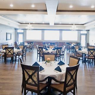 An elegant restaurant dining room with neatly arranged tables and chairs, featuring soft lighting.