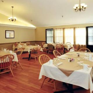 A well-lit restaurant dining room with arranged tables and wooden chairs.