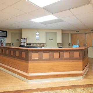A modern hospital reception area featuring a wooden desk and bright lighting.