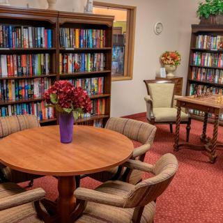A cozy library with bookshelves and a reading area featuring tables and chairs.