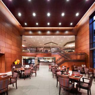 A modern restaurant interior features wood paneling, ample seating, and elegant lighting.