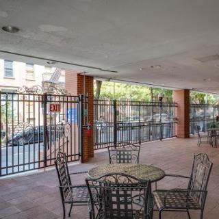 An inviting outdoor seating area with tables and chairs, enclosed by a fence in an urban setting.