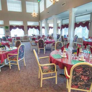 A spacious dining area with elegantly set tables and chairs, featuring large windows and decorative interior elements.