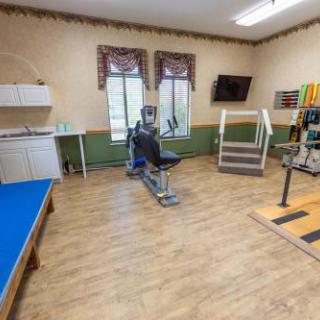 A spacious therapy room equipped with exercise machines and a comfortable setting for rehabilitation.