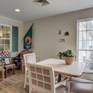 A cozy dining area with a table and chairs, adorned with an indoor plant and illuminated by natural light from a nearby window.