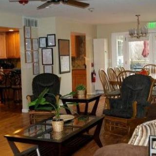 A cozy living room with a connected dining area featuring comfortable seating, wooden floors, and decorative elements.