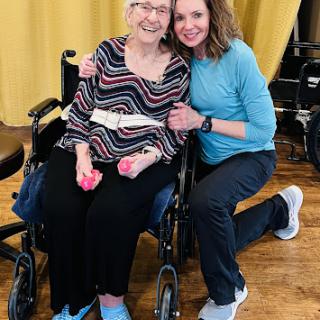 A joyful moment shared between a caregiver and an elderly individual during a wellness activity.
