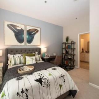 A modern bedroom with stylish decor and artwork above the bed.