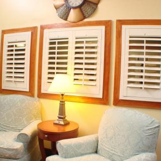 A cozy living room corner with two armchairs, a lamp on a side table, and decorative shutters on the wall.