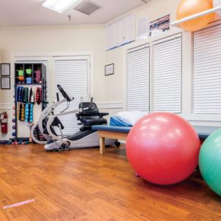A well-equipped gym room featuring exercise balls and a stationary bike.