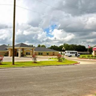 A suburban building with a bus parked nearby under a cloudy sky.