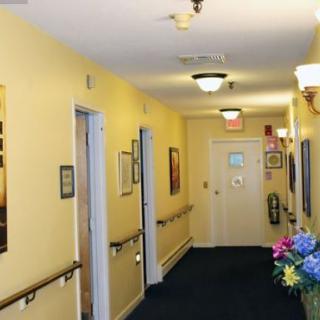 A hallway with yellow walls, several doors, and overhead lighting.