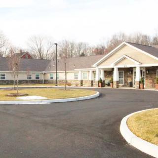 An exterior view of a building with a circular driveway and surrounding landscape.