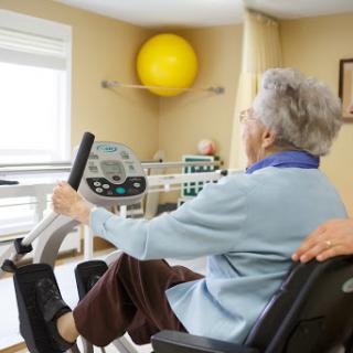An elderly individual participating in a rehabilitation exercise on a stationary bike, promoting health and fitness.