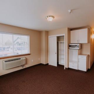A small apartment room with a kitchenette and window view.
