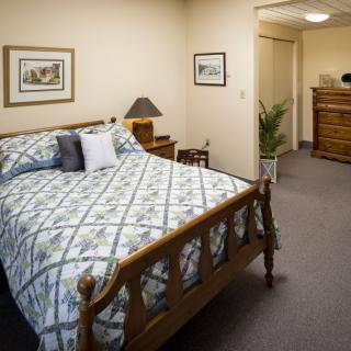 A cozy bedroom with a wood-framed bed, patterned bedding, and warm lighting.
