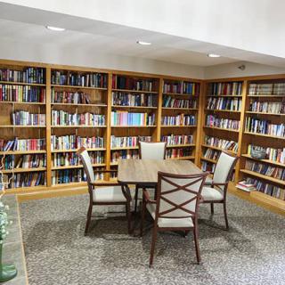 A cozy library corner with bookshelves, a table, and chairs for studying.