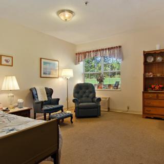 A cozy living room with armchairs, a lamp, and a window view.