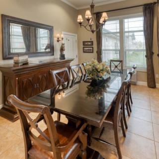 Elegant dining room with a large table, chairs, and a chandelier.