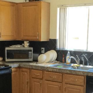 A cozy kitchen with wooden cabinets, a microwave, and dishes near the sink.