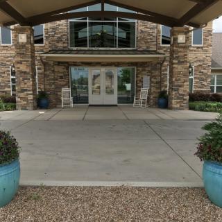The entrance of a building with a stone facade and large planters.