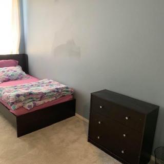 A minimalist bedroom with a single bed and a small dresser.
