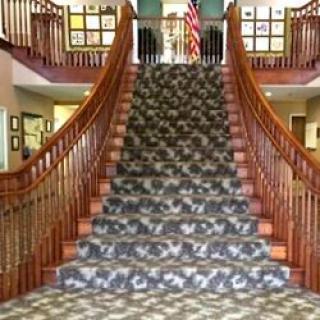 Grand staircase with ornate wooden railings and patterned carpet.