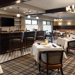 A cozy restaurant interior with a bar and neatly arranged dining tables.