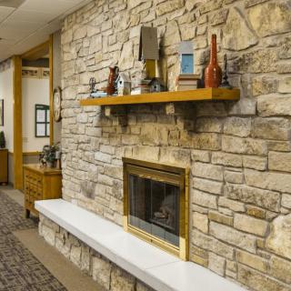 A cozy stone fireplace adorned with decorative items on a wooden mantel.