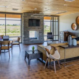 A modern living room with large windows, a central fireplace, and stylish furniture.