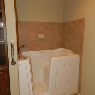 A bathroom featuring a walk-in bathtub with tiled walls.