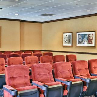 An empty theater room with red seats and framed artwork on the walls.