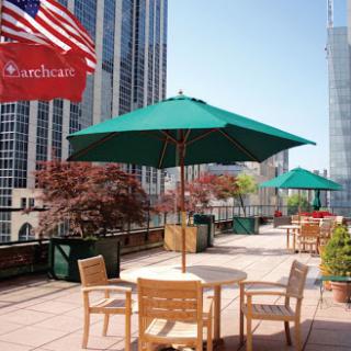A serene outdoor terrace with green umbrellas and city views, perfect for relaxation.